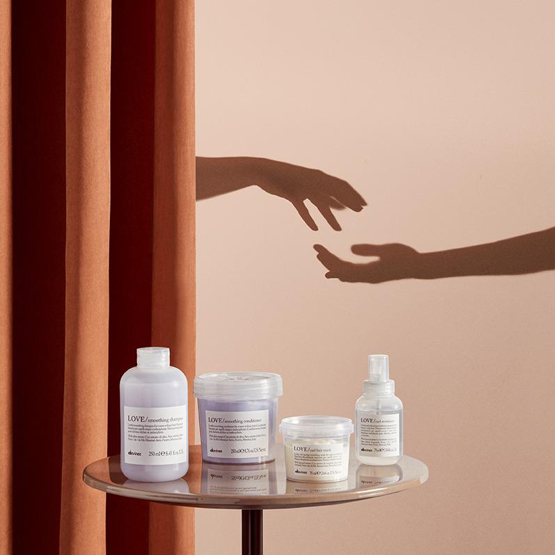 Davines-producten op een rond tafeltje voor een warmgekleurde achtergrond